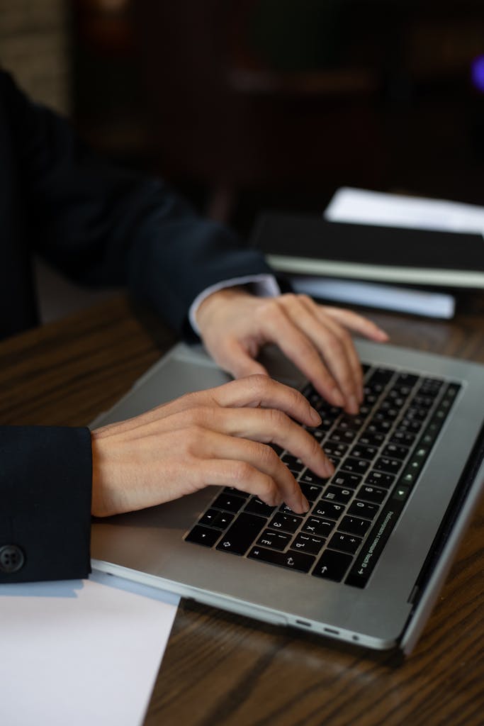 Detailed shot of hands typing on a laptop keyboard in an office setting, highlighting modern technology.